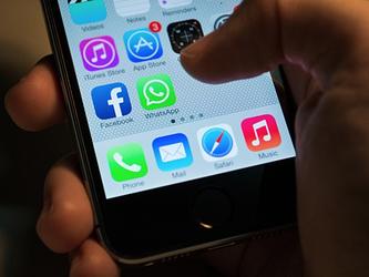 hand holding a smartphone with thumb hovering near whatsapp icon